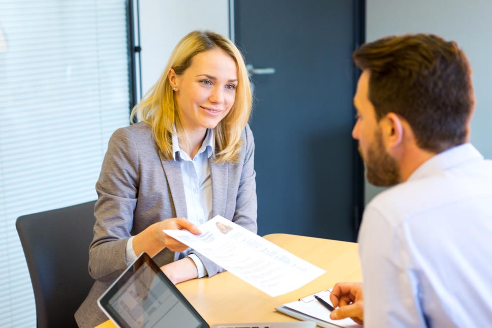 Woman handing over her CV in a job interview